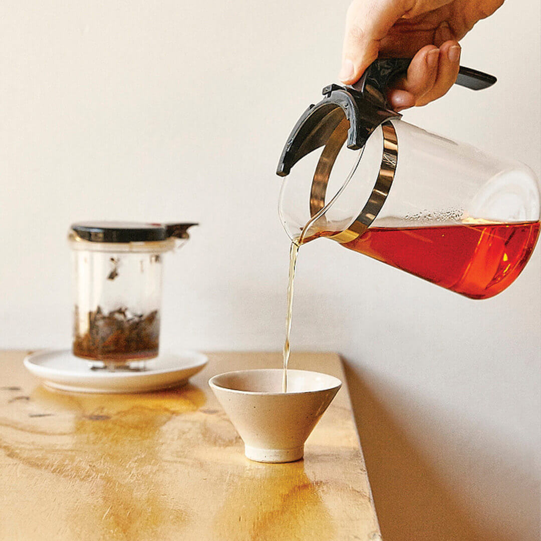 Red Mystic tea being poured into a tea cup from infuser